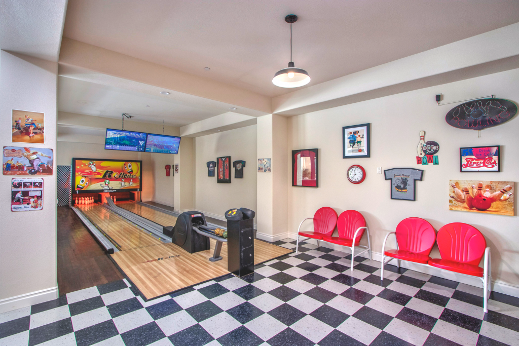 A '50s style bowling alley with checkered floors, bright red seats, and a custom bowling alley