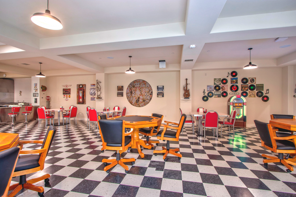 A '50s inspired dining area with black and white checkered floors, game tables, and a jukebox in the back