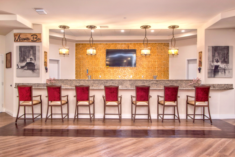 A luxury gold-backed bar with red-backed barstools